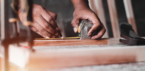 Carpenter working with equipment on wooden table, And measurement of a wooden plank