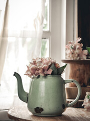 selective focus of vintage and rustic green enamel jug filled with flower