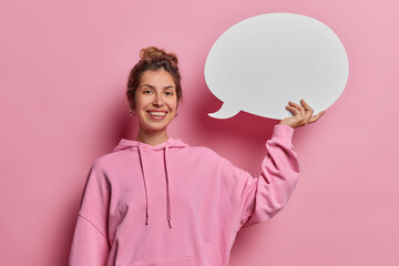 Young European woman holds an empty speech bubble, poised to express her opinion and provide...