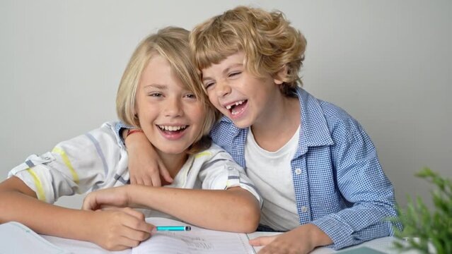 Primary elementary middle school boy girl siblings studying at desk table, writing in book and tablet at class home homework acquiring information knowledge Back to school.