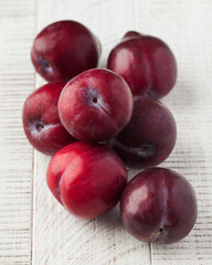 Ripe juicy plum on a white wooden background. Fruit concept