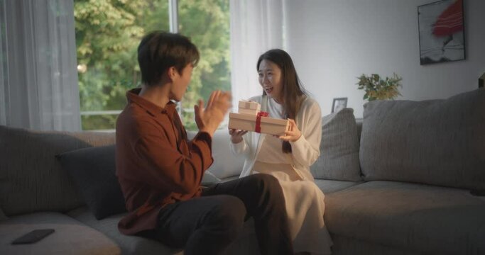 남자친구가 여자친구에게 선물을 준 뒤 웃으며 카메라를 보는 모습