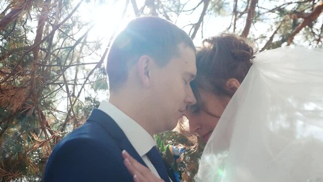 Bright sunbeams illuminate a handsome man giving his girlfriend a charming kiss.