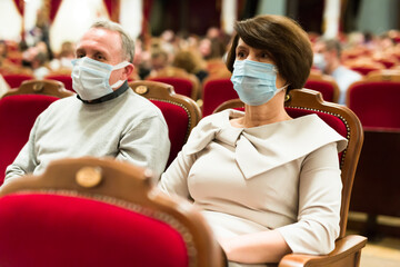 Caucasian couple senor and senora in antivirus mask in theater hall