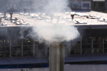 Close-up of smoking tin pipes against the background of industrial premises, houses
