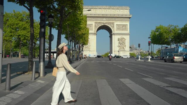 Young woman walking in the city against the backdrop of the Arc de Triomphe