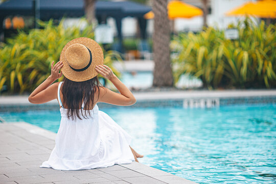 Young beautiful woman enjoying summer vacation in infinity luxury swimming pool