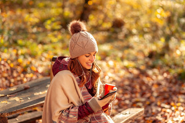 Woman using smart phone while spending autumn day outdoors
