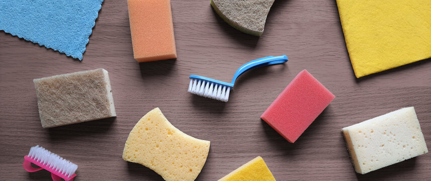 Hardware store banner. Flat lay. Goods for cleaning. Kitchen sponges, washcloth, scrubbing brush on wooden table background. Top view. Home cleaning service concept. Header for website, blog, article
