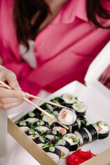 girl take out salmon rolls from a box of rolls