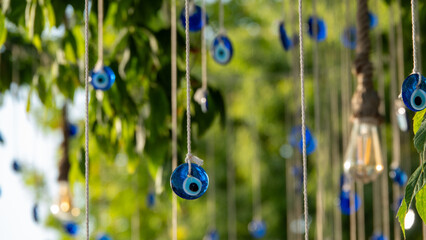 Blue evil eye beads hanging with a rope from a tree branch. Traditional Evil Eye Amulet. A national...