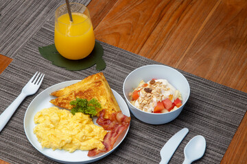 Kids menu - omlet, pancakes with maple syrup, muesli with yoghurt and glass of fresh squuzed orange juice served on the restaurant table with plastic kids friendly eating utensil. - obrazy, fototapety, plakaty
