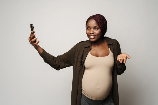 African pregnant smiling young woman making phone video call