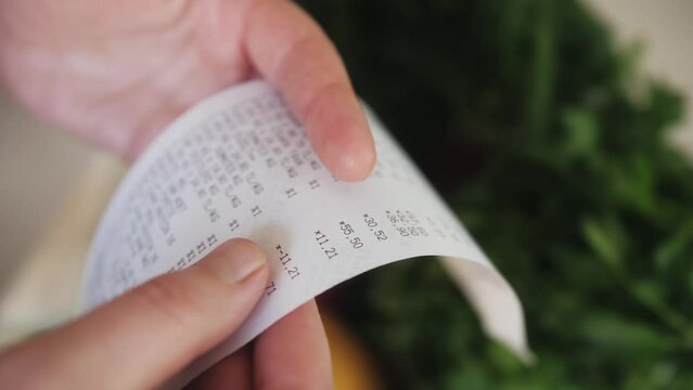 The buyer holds a purchase receipt in hands, checks purchases and prices.