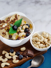 Healthy healthy breakfast. Fruit salad with banana, cashew, blueberry, chocolate and corn flakes. Fitness recipe for healthy balanced breakfast. Still life. Top view.