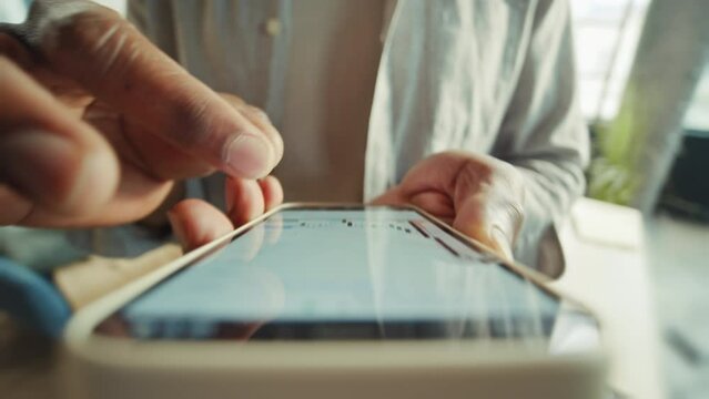 Close-up shot of unrecognizable African American man holding smartphone in hands, reading article on internet. Male hands increasing text. Businessman in casual outfit browsing on device on blurred
