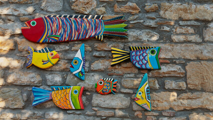 Colorful wooden fish ornaments on the stone wall. Modern Wood Art. Handmade carved from wood