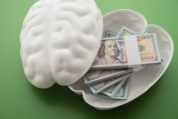 Many US dollar banknotes bill inside brain head on green background. Smart intelligence brain make...