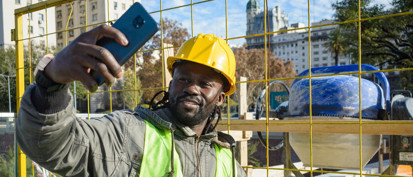 banner of african man construction worker taking a selfie with the machines in the background - Powered by Adobe