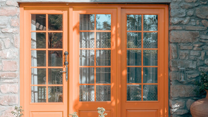 orange painted entrance door to the stone house in Gokceada Imbros island. 