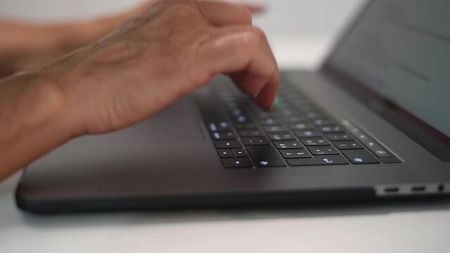 Woman fingers tapping on a modern laptop keyboard, slow motion