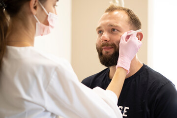 The cosmetologist marks with a pencil the points for beauty injections of botulinum therapy on the face of a man. Concept Plastic surgery and cosmetology for men with copy space