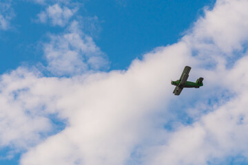 Green biplane, retro airplane flying in blue sky at Air Show. Performance, extreme, aerobatic, sport and aircraft concept