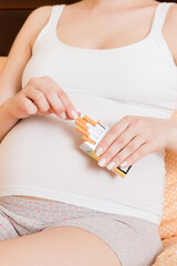 Pregnant woman smoking cigarette at home in bed
