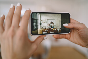 Crop woman taking photo of family on smartphone