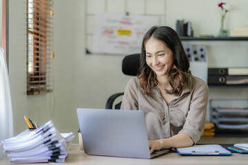 Asian woman working on documents on laptop at work sitting at desk planning financial report business plan investment Financial business analysis and research concepts.