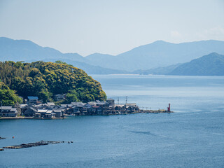 快晴の伊根の舟屋と赤灯台の風景