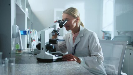 Scientist woman looking under the microscope worker in the laboratory. Medicine, biotechnology research. Pharmacology