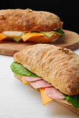 Chiabatta sandwich with ham and cheese on wooden board