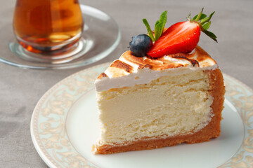 Piece of cake on plate with cup of tea on gray table