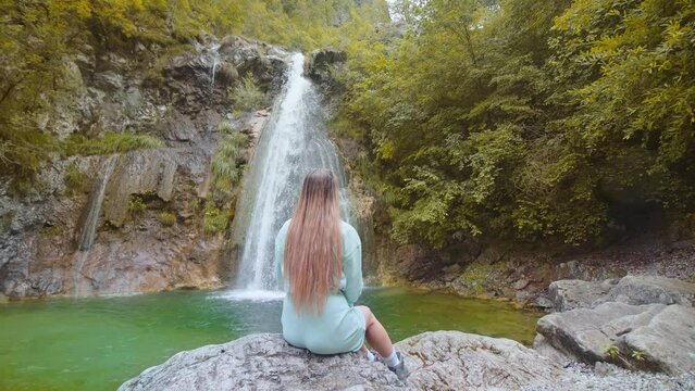 Woman sitting in front of the waterfall