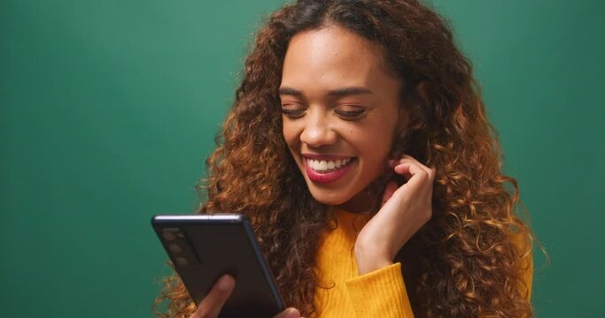 Beautiful young woman texts boyfriend, flirty message relationship, green studio