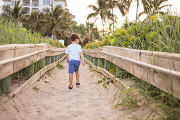 boy walking in the board walk at a Beach in palm beach florida singer island by the ocean point  - Powered by Adobe