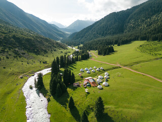Top view of yurts nomad village in Jety-Oguz gorge in Kyrgyzstan. Karakol national park. Traditional nomad's yurts on beautiful mountain meadows in the green mountains in Karakol area in the summer. 