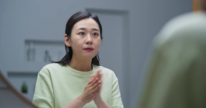욕실에서 거울을 보며 수분 크림을 바르는 젊은 여성