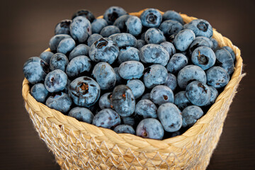 A basket of fresh blueberries on a dark background. Berries, healthy food. Close-up. Side view.