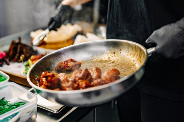 chef cooking chicken wings in a sauce in the kitchen
