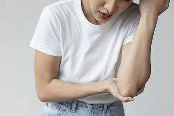 Asian woman suffering from tennis elbow syndrome, pain from elbow injury, isolated background