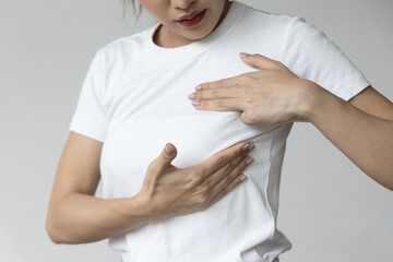Asian woman checking her chest at home, concept of breast cancer awareness month, breast cyst or...