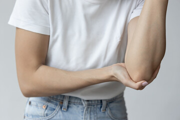 Asian woman suffering from tennis elbow syndrome, pain from elbow injury, isolated background