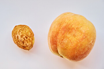 Fototapeta premium A close-up of a peach and its stone on a white background. View from above