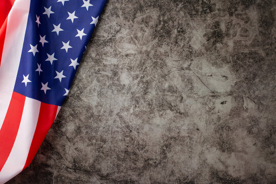 Embracing the spirit of the American public holiday: A captivating top-down photograph showcasing the American flag on a grunge textured grey concrete background. Ample copy-space for adverts or text