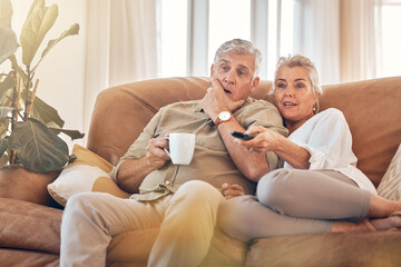 Senior couple, watching tv and sofa in relax for streaming, movie or series in living room at home. Elderly man and woman with coffee and remote together for changing channel and online entertainment