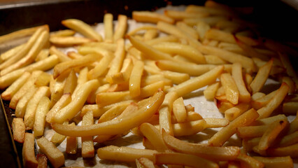 Closeup of pouring oil on frying french fries in oven. Fast food, healthy nutrition, cooking in oven.