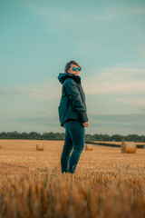 Woman wearing sunglasses hiking in a field, agricultural setting, harvest outdoors landscape scene