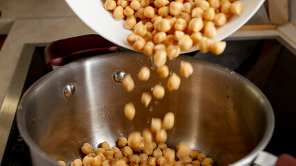 Slow motion of pouring soaked chickpea in pot with water. Legume, healthy nutrition, vegan food.